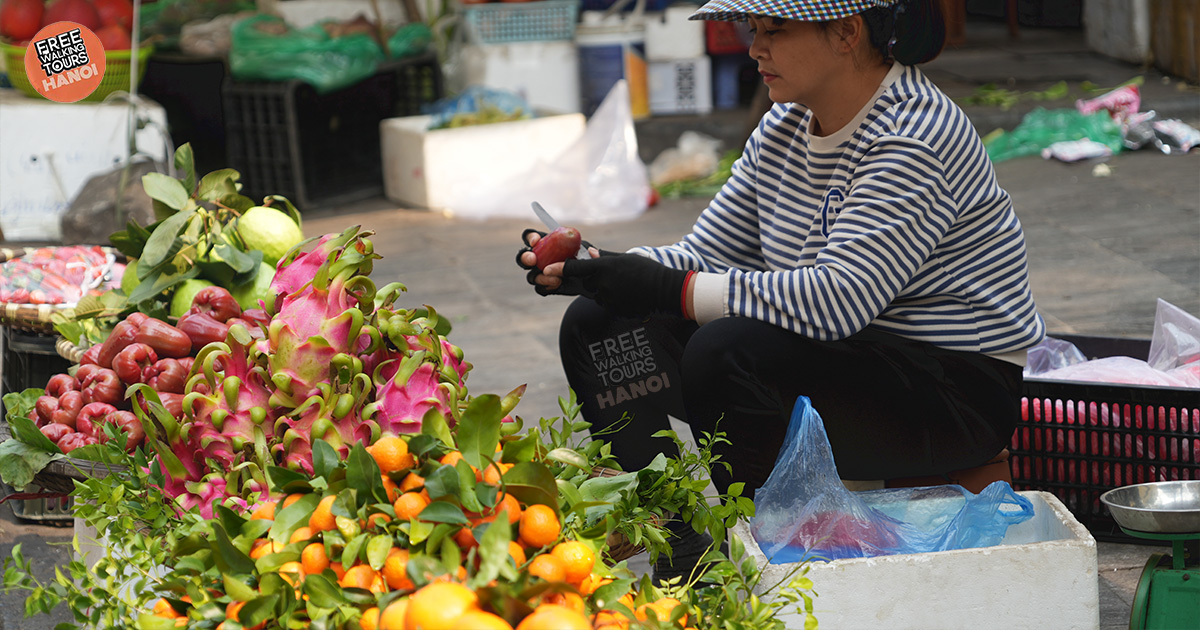 Vietnamese woman selling fresh fruit at a traditional Hanoi market